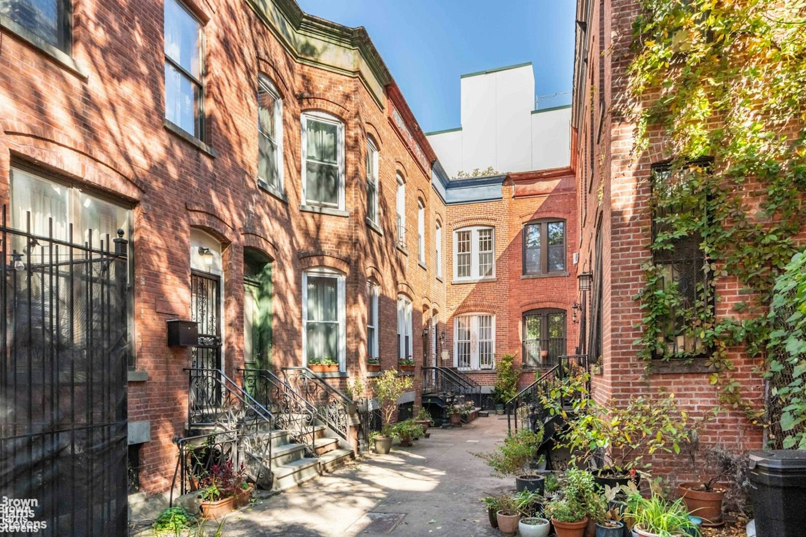 Behind a discreet wrought iron fence, discover a paved street lined with charming 1899 red brick Italianate townhouses.