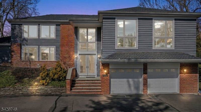 Commanding atop a lush, elevated lot bordering 1.