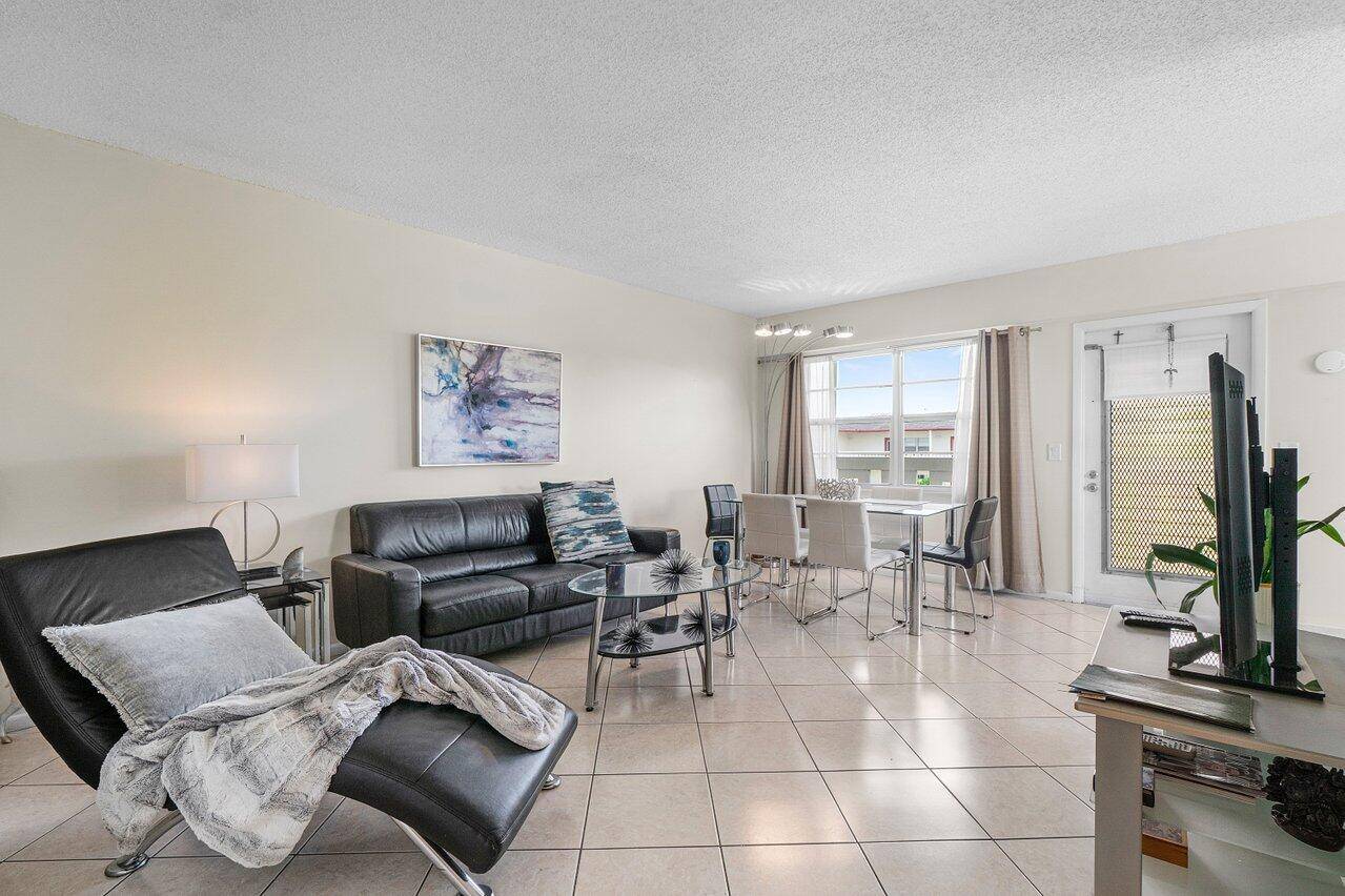 Top floor corner unit in Century Village Boca Raton featuring 2 bedrooms, impact windows, and an updated kitchen with granite counters, white cabinets, and stainless appliances.