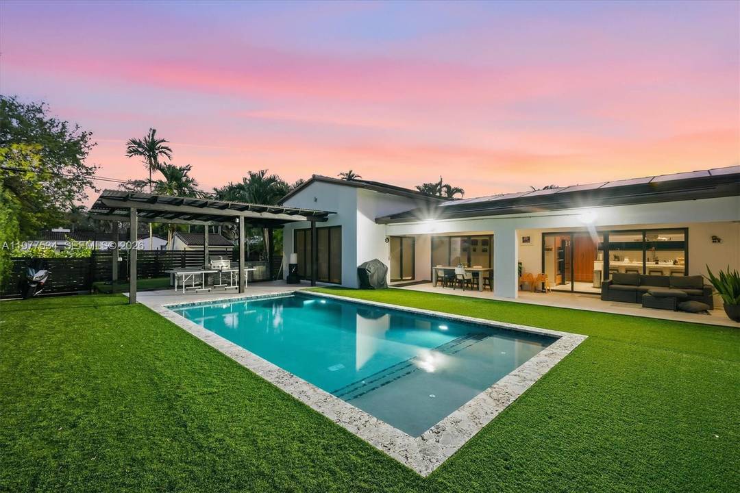 Introducing the Main Street Modern A beautifully remodeled family home in the heart of Miami Shores, showcasing a striking white stone fac ade, and gated driveway with timeless curb appeal.