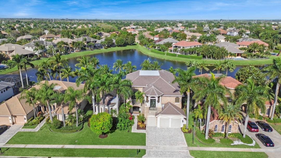 Magnificent former builder's model in Wellington's upscale Versailles sits on a breathtaking lakefront lot with an infinity edge heated saltwater pool and spa, travertine tile patio, outdoor kitchen and mango ...