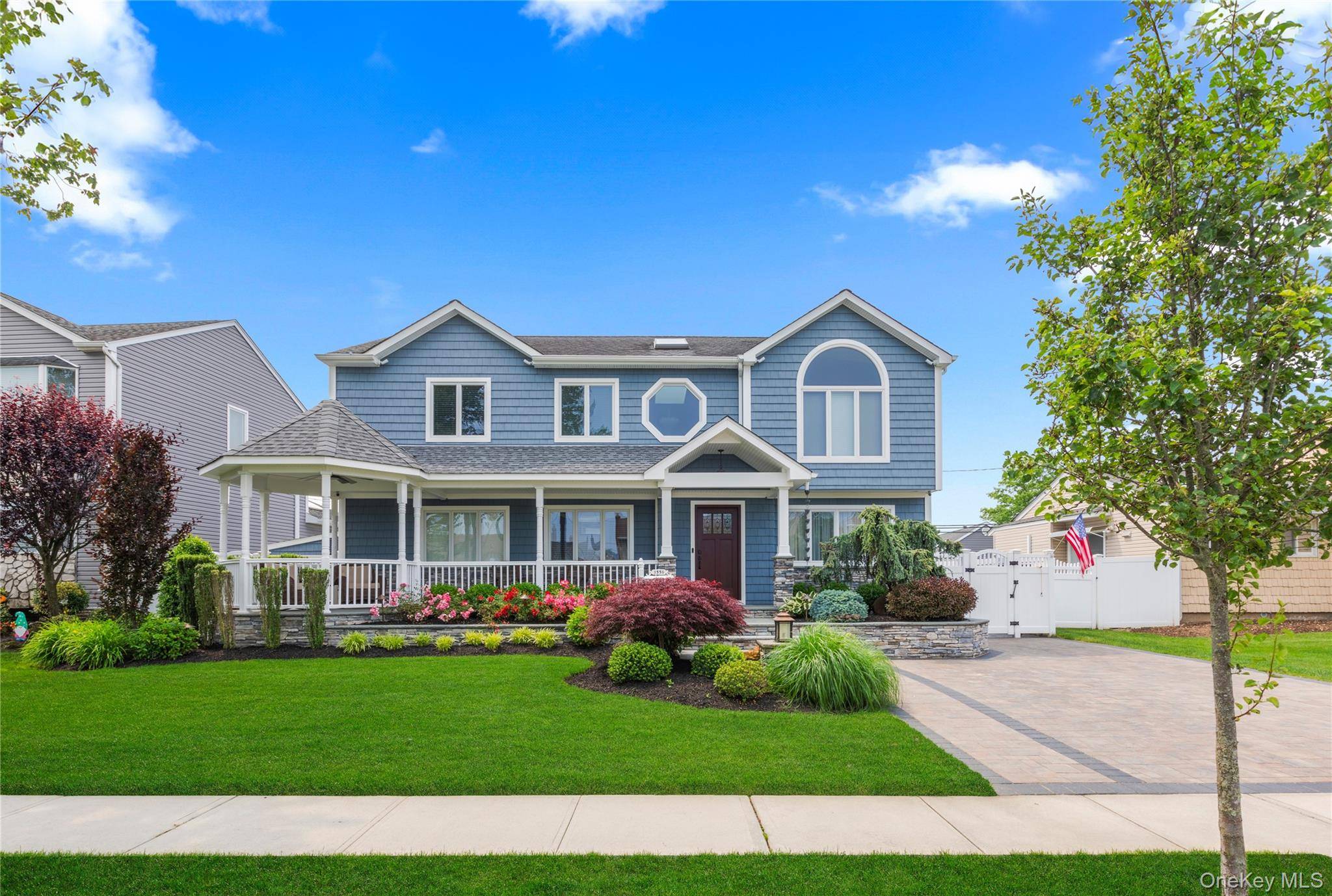 Nestled on a picturesque street, this beautiful home enchants with its stunning blue facade, lush mature landscaping, a welcoming front porch, and tasteful stone accents.