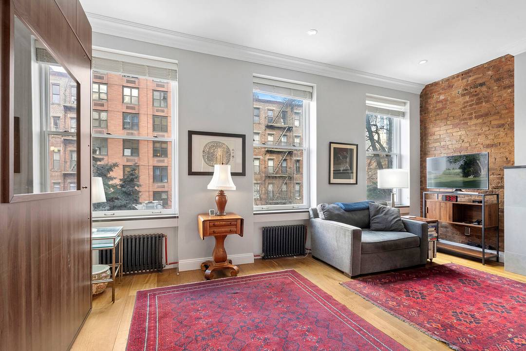 Furnished Beautifully renovated studio with high ceilings, a decorative fireplace, and open northwestern views through three oversized windows.