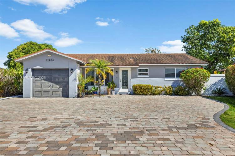 Beautifully remodeled home in West Boca Raton featuring an expansive paved driveway and a cozy backyard with low maintenance landscaping.