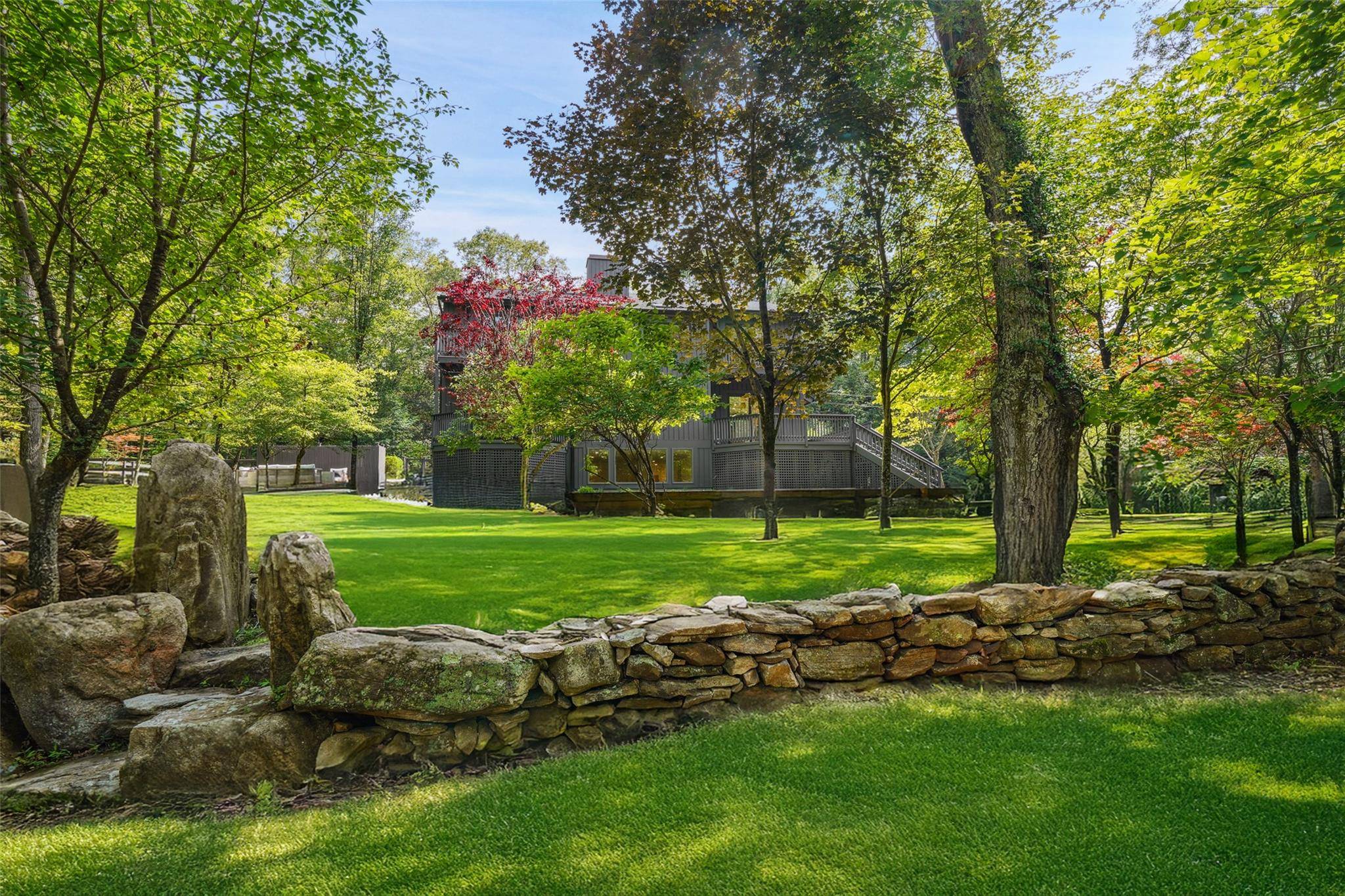 Fully renovated modern on storybook land in Pound Ridge with picturesque pond, walking trails, footbridges, natural rock outcroppings, and a gorgeous Shoreline Pool with built in spa and automatic cover.
