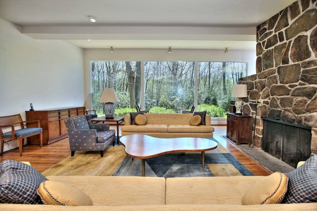 Discover the charm of this mid century modern home, bathed in natural sunlight thanks to large windows that frame stunning views of the lush landscaping and nature outside.