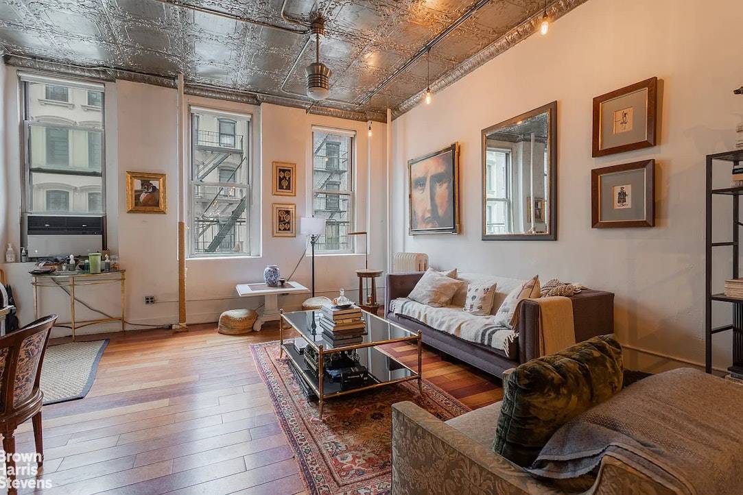 This spacious 1, 446 sq ft full floor loft features 12 foot original tin ceilings, skyline views, exposed brick, and classic bohemian design in prime Tribeca.