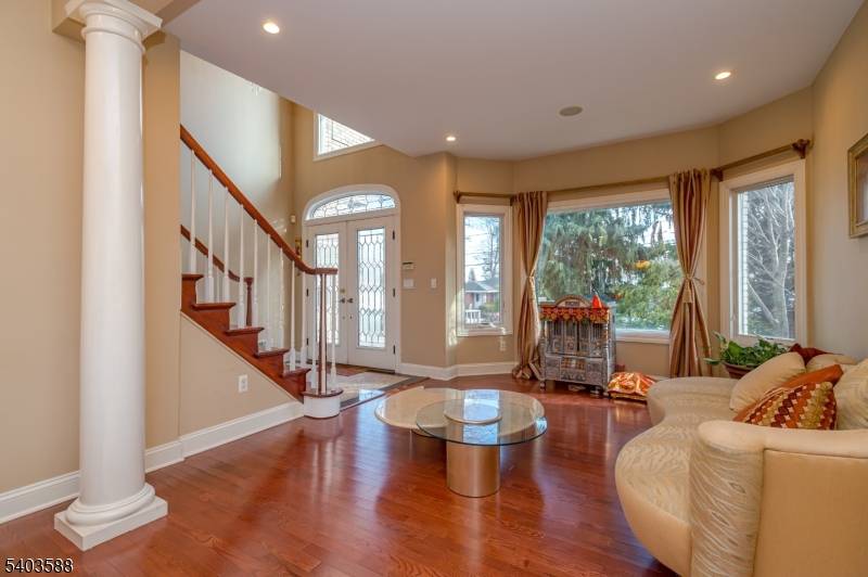 East facing colonial home featuring a classic brick front, paver driveway, and inviting walkway leading to a bright, open foyer with a stunning chandelier and abundant natural light.