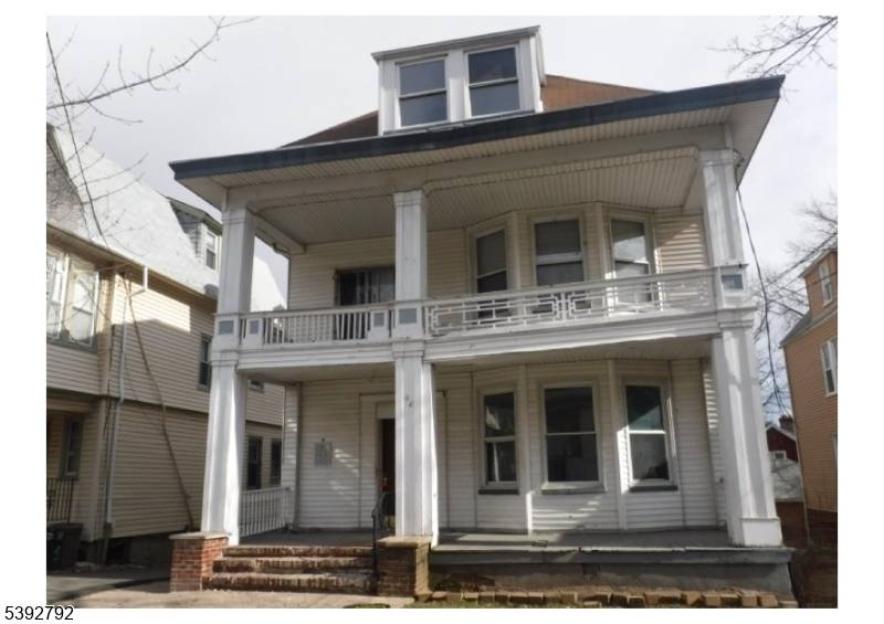 Large multi story 2 family house with a covered front porch and balcony area.