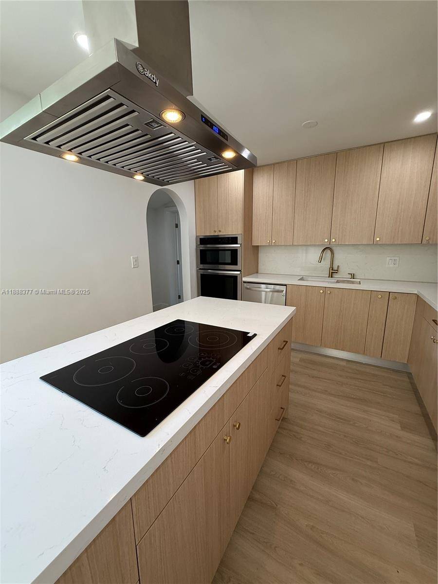 Step into this beautifully renovated home featuring a custom kitchen with all wood cabinets, a convenient spice rack, and a spacious island complete with an over the range hood and ...