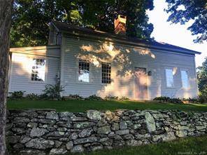 Quintessential New England farmhouse on dirt road.