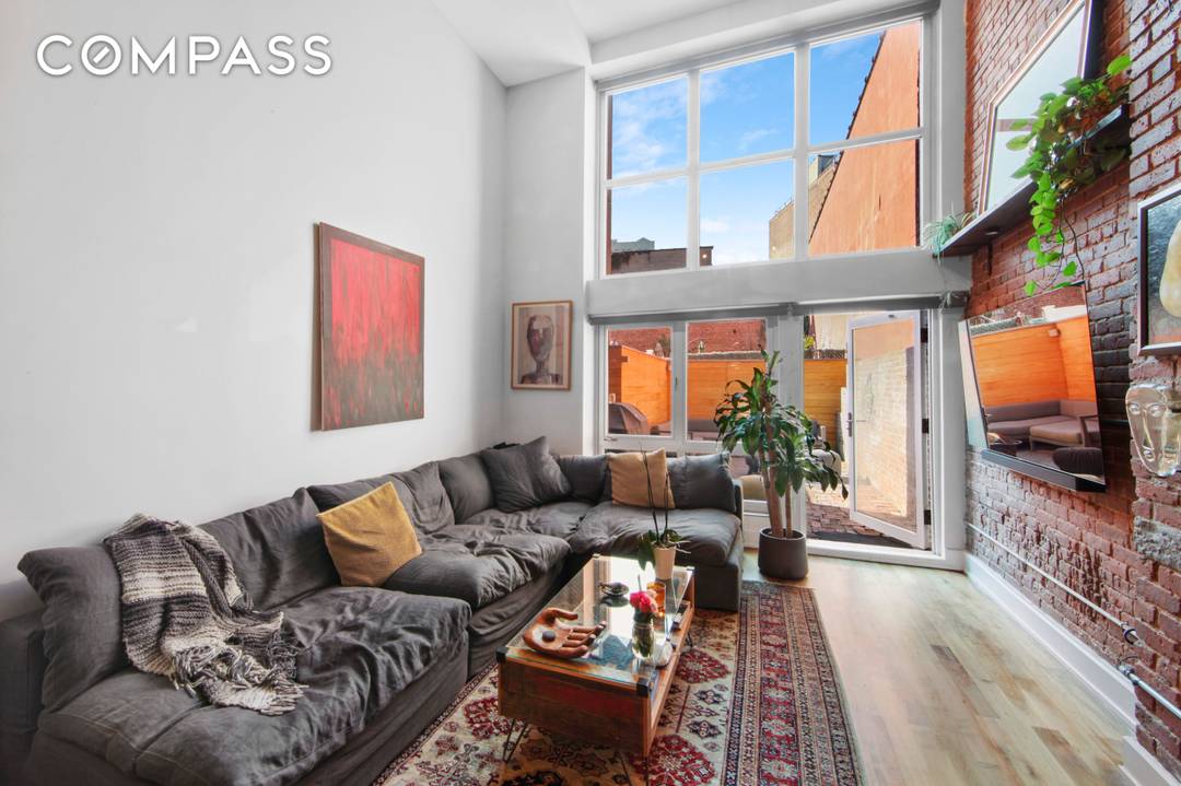 Loft 1C offers soaring double height ceiling height of nearly 17 feet, Southern exposed floor to ceiling windows, steel stairs railings, original exposed brick and a private backyard.