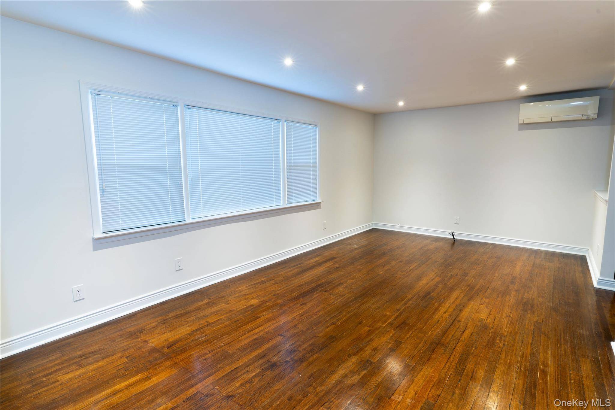 This charming apartment offers a spacious living area with sleek hardwood floors and abundant natural light, making it feel bright and welcoming.