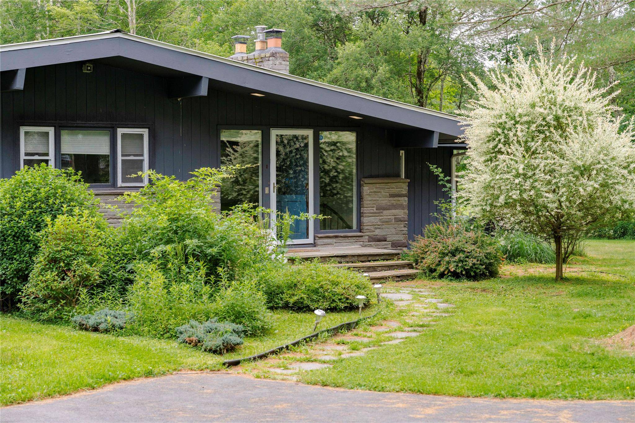 At the end of a long, private drive, this elegant mid century home sits tucked into six acres of open lawn, forest, and filtered light.