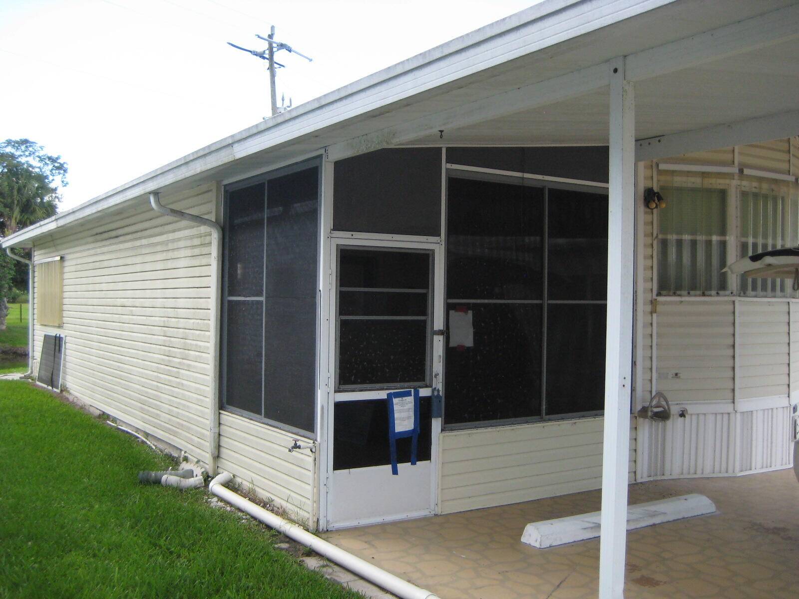 Manufactured home in the desirable 55 gated community of Ancient Oaks RV Resort in Okeechobee, featuring an enclosed patio for extra living space, serene pond views, and backyard privacy.
