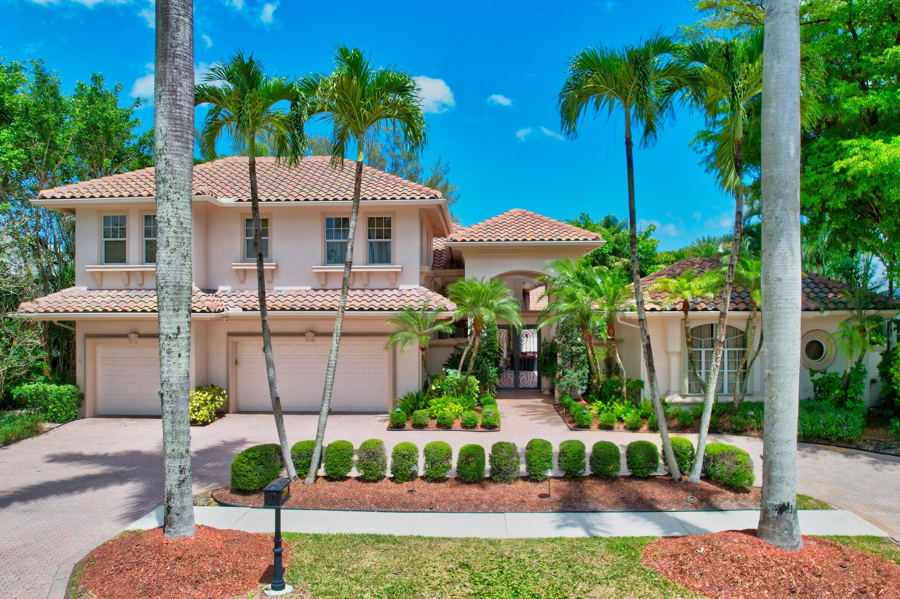 Beautiful two story courtyard style home in Boca Grove featuring six bedrooms with ensuite baths, including a one bedroom one bath detached guesthouse.