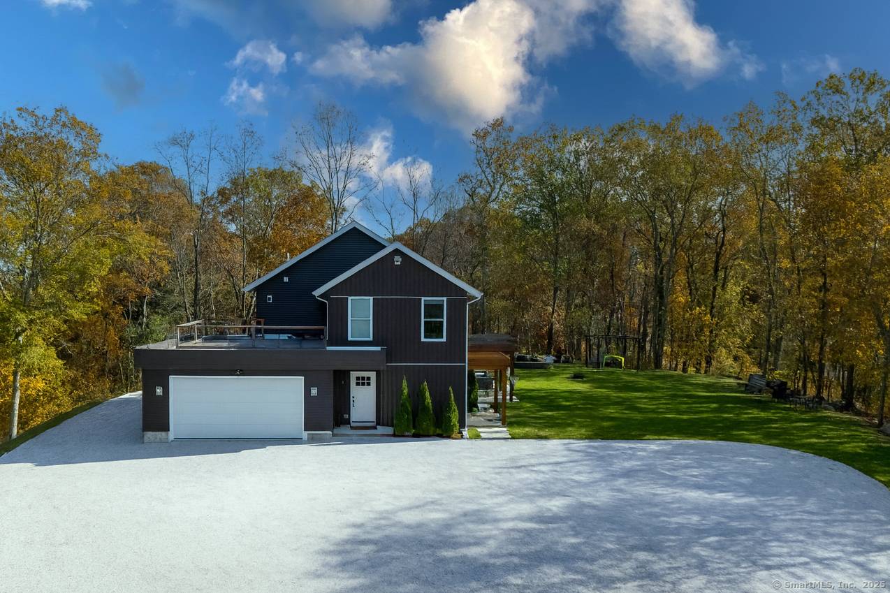 Modern 2020 built home set on a private, wooded acre with a long driveway and open lawn space.