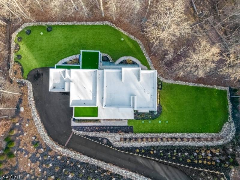 This striking two story contemporary home greets you with a dramatic foyer featuring rich wood paneling, a sculptural lighting fixture, and a custom staircase with glass railings that set the ...