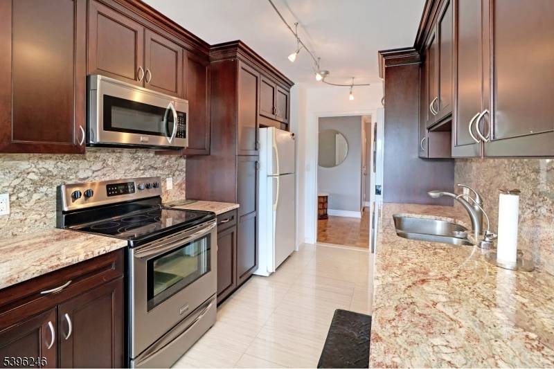 One to see Renovated 2 bed, 2 bath boasts modern upgrades Galley kitchen features rich, dark wood cabinetry, light granite countertops with a matching backsplash.