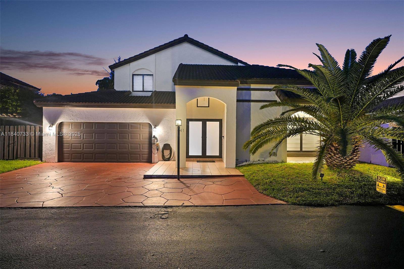 Backyard living takes center stage with a heated, resort style pool and spa featuring color changing LEDs, surrounded by tropical palms and privacy hedges.