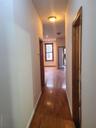 Hall with baseboards, a baseboard heating unit, and hardwood / wood-style floors