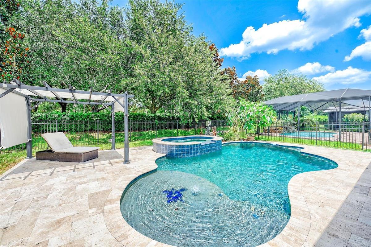 Stunning pool featuring a sunshelf with a umbrella holder and bubbler as well as an oversized hot tub/spa.