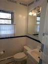 Bathroom with toilet, tile patterned floors, tile walls, and a healthy amount of sunlight