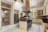 Kitchen with cream cabinets, light tile patterned floors, crown molding, stainless steel appliances, and glass insert cabinets