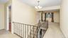 Hallway featuring baseboards, light carpet, an upstairs landing, and a chandelier