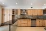 Kitchen featuring light wood cabinetry, dark speckled countertops, and a tiled backsplash