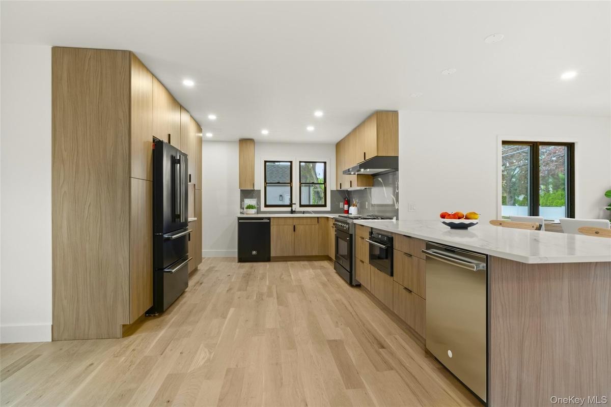 Contemporary kitchen featuring wood-finish cabinetry, a large kitchen island with a stone-finish countertop, stainless steel appliances, and wood-fini