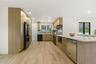 Contemporary kitchen featuring wood-finish cabinetry, a large kitchen island with a stone-finish countertop, stainless steel appliances, and wood-fini
