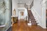 Two-story foyer with hardwood flooring, a grand staircase featuring wood and wrought iron railings, decorative wainscoting, and an arched entryway