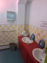 Half bathroom featuring double vanity, tile walls, wainscoting, and baseboard heating