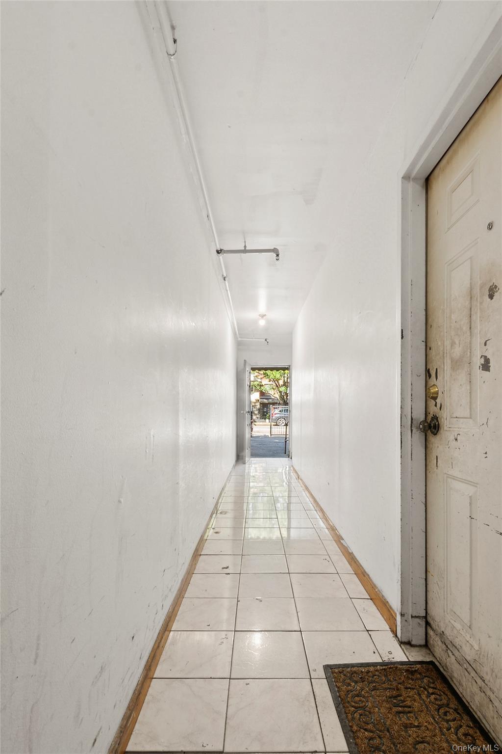 Hall with light tile patterned flooring and baseboards