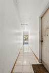 Hall with light tile patterned flooring and baseboards