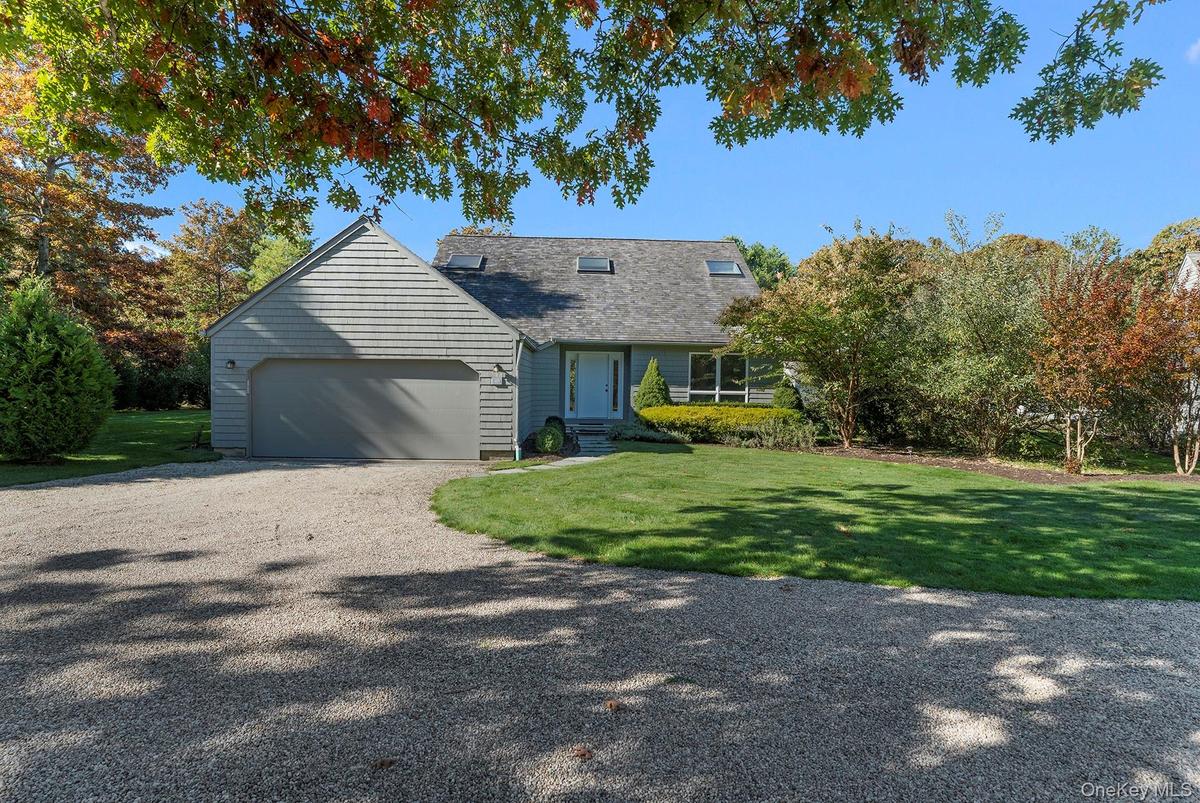 View of front of property featuring driveway, a front yard, a garage, and a shingled roof