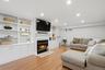 Recessed lighting, wood-finish flooring, built-in shelving, built-in cabinetry, and a fireplace with a mantel