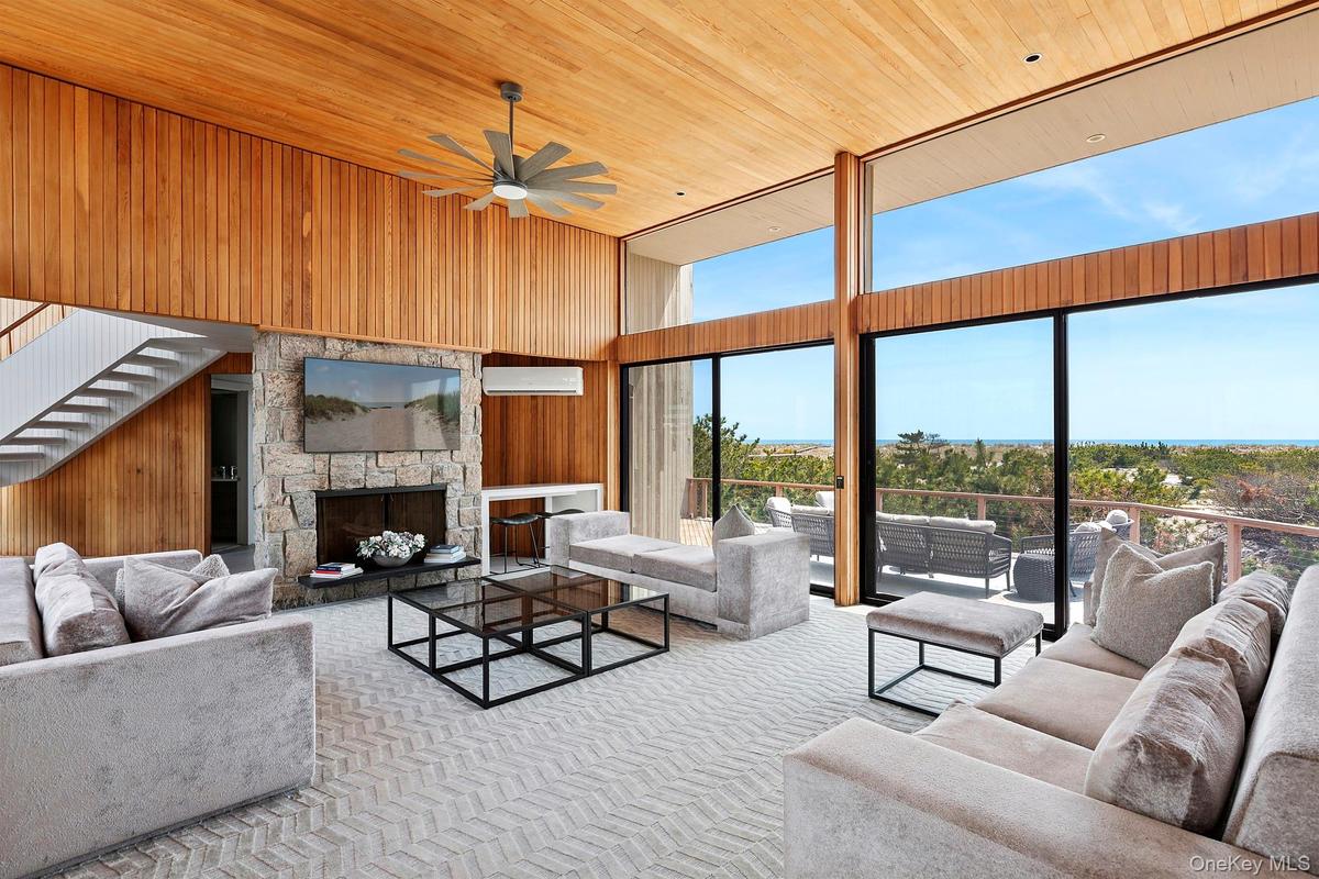 Carpeted living area with wood ceiling, a high ceiling, a wall mounted air conditioner, a wealth of natural light, and ceiling fan