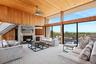 Carpeted living area with wood ceiling, a high ceiling, a wall mounted air conditioner, a wealth of natural light, and ceiling fan