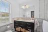 Bathroom with tile walls, vanity, a baseboard heating unit, a wainscoted wall, and a stall shower