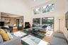 Living room with light wood finished floors, a towering ceiling, and a baseboard radiator