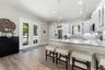 Open-concept kitchen with solid-wood cabinetry, granite countertops, stainless steel appliances, and custom lighting including under-counter kitchen l