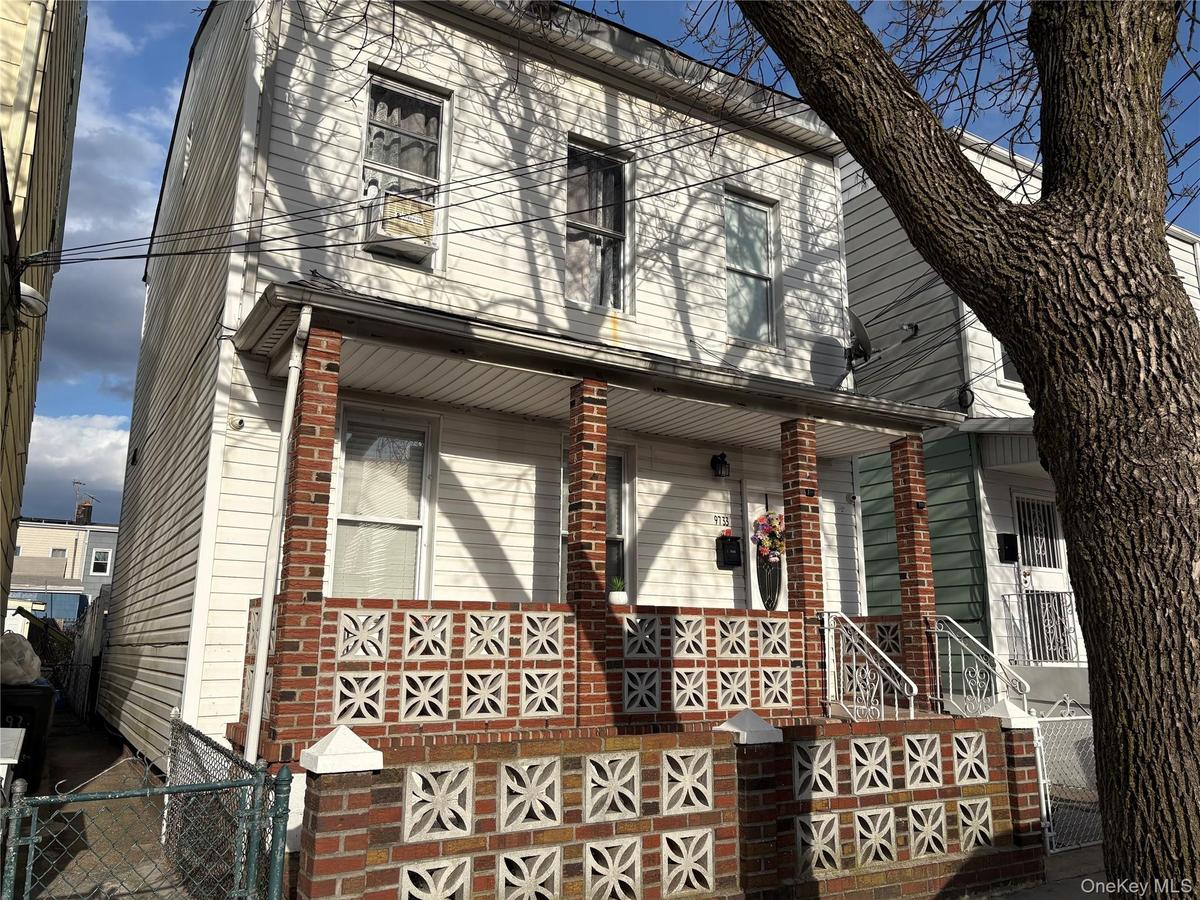 Two-story white siding residence featuring a covered front porch supported by brick pillars