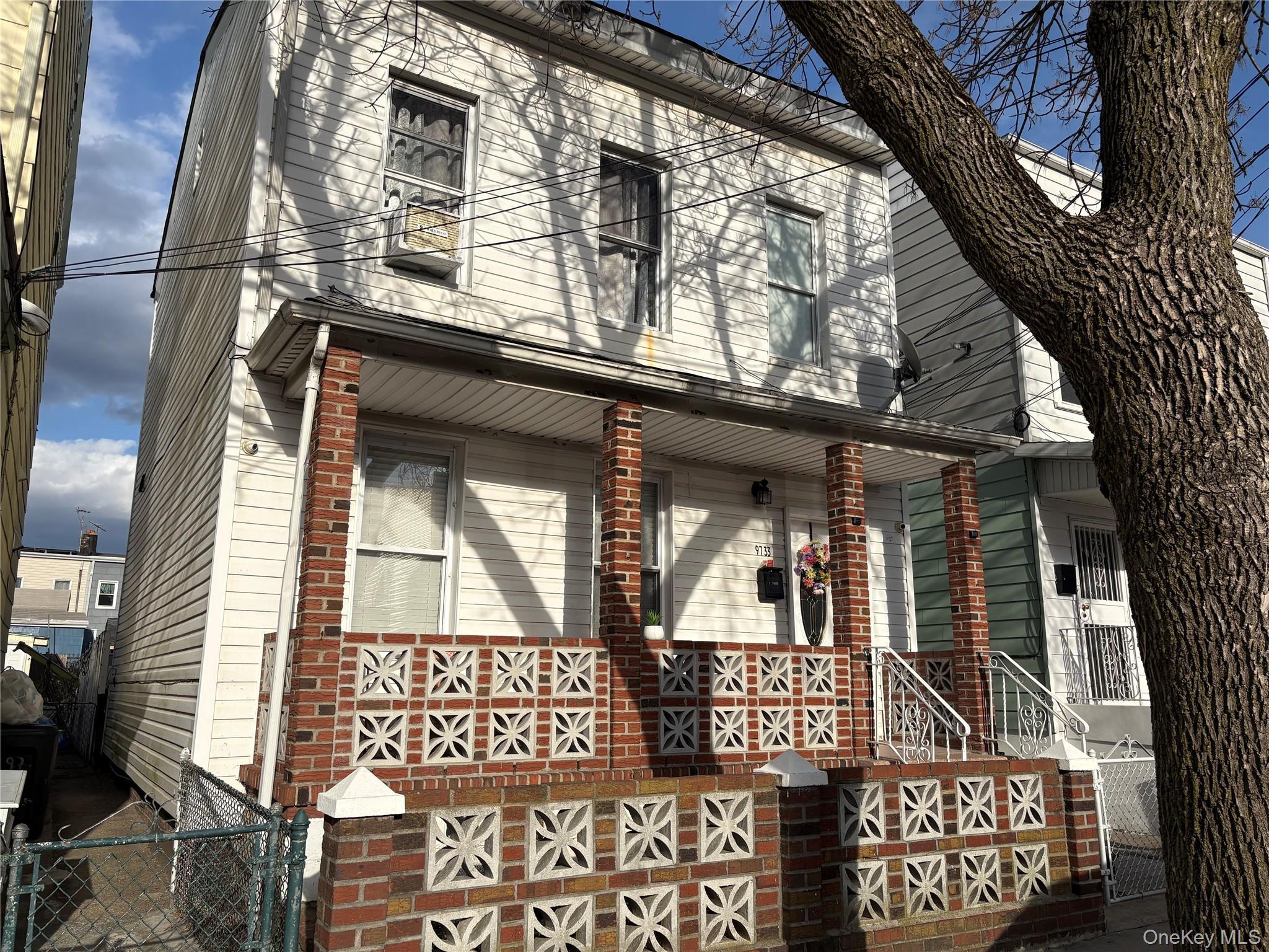 Two-story white siding residence featuring a covered front porch supported by brick pillars