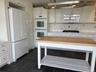 Kitchen featuring a butcher block island, white cabinetry, slate tile flooring, and integrated wall ovens