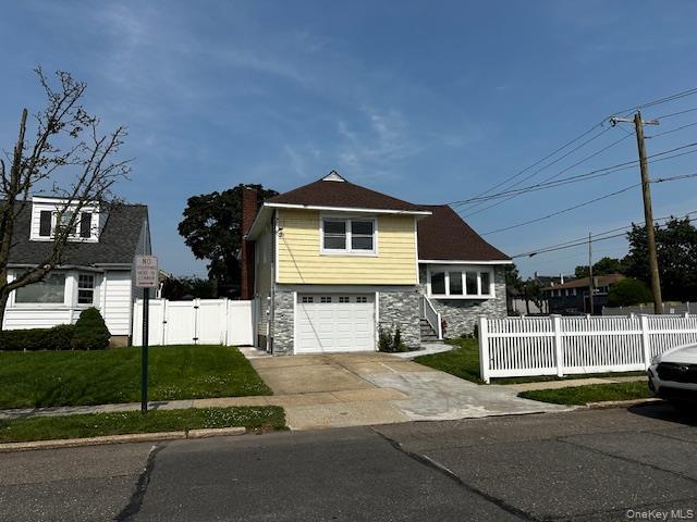 View of front of home with stone siding, a garage, driveway, a gate, and a chimney