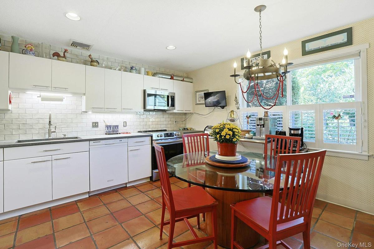 Kitchen with stainless steel appliances, backsplash, white cabinetry, terracotta tile floors, and recessed lighting