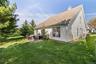 Expansive backyard featuring a stone patio, manicured lawn, and mature trees