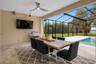 Oversized covered lanai designed for year-round outdoor living, dining and entertaining with peaceful water front views. Color of area rug has been vi